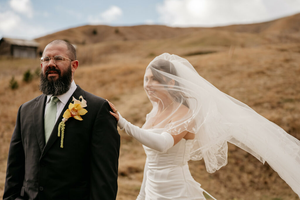 Bride surprises groom in mountainous location.