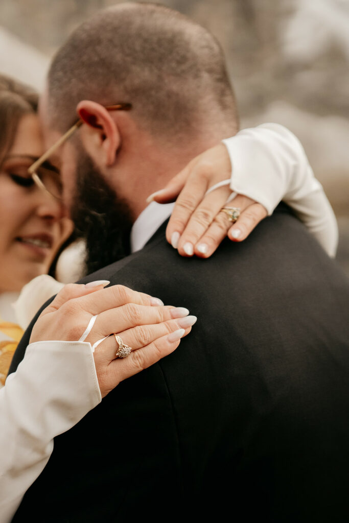 Close-up of couple embracing and showing wedding rings.