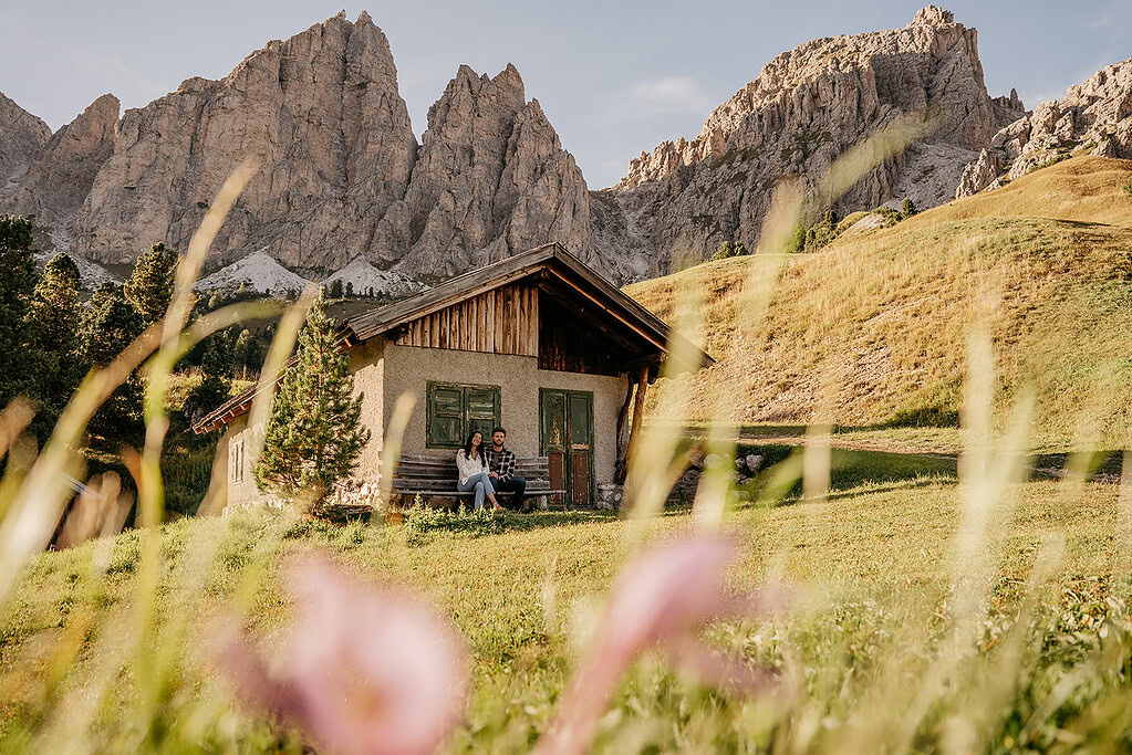 Couple sitting outside cabin in mountain valley