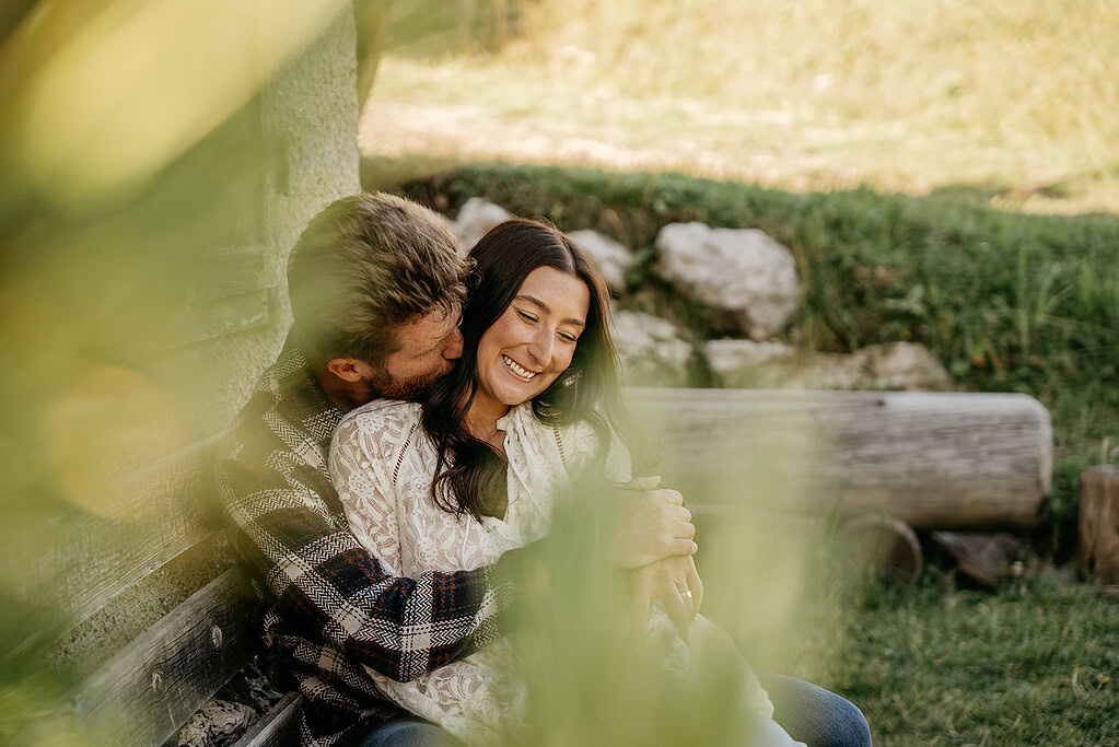 Couple embracing outdoors on wooden bench.