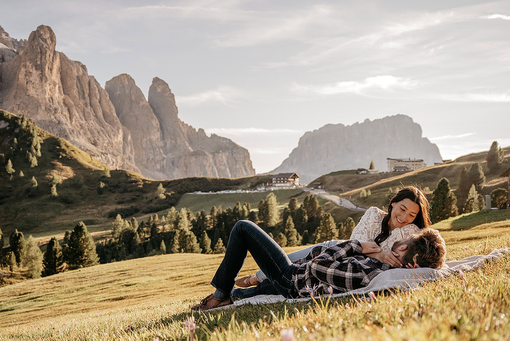 Couple relaxing on grassy hill with mountains.