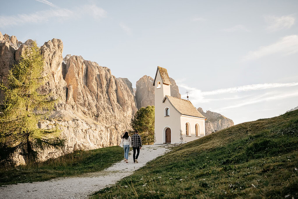 Couple walking to chapel in mountain landscape