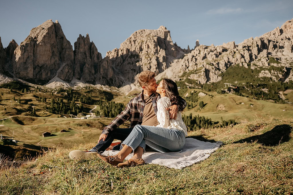 Couple kissing on mountain picnic blanket