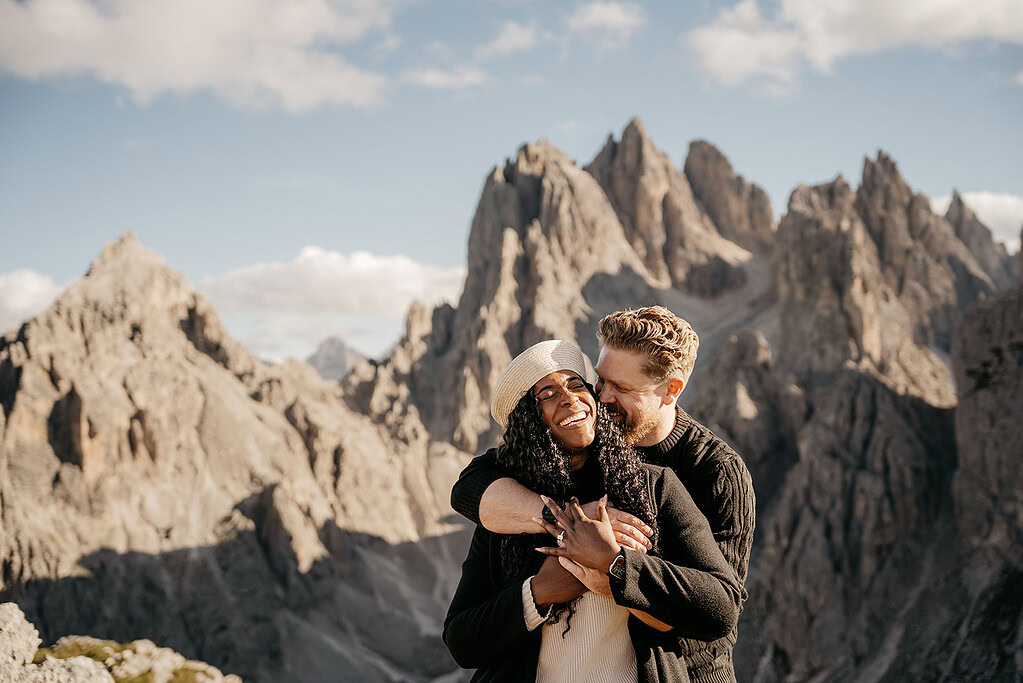 Couple embracing in front of scenic mountains.