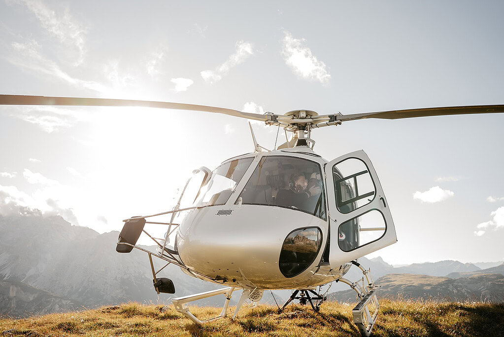 Helicopter on grassy mountain with open door.