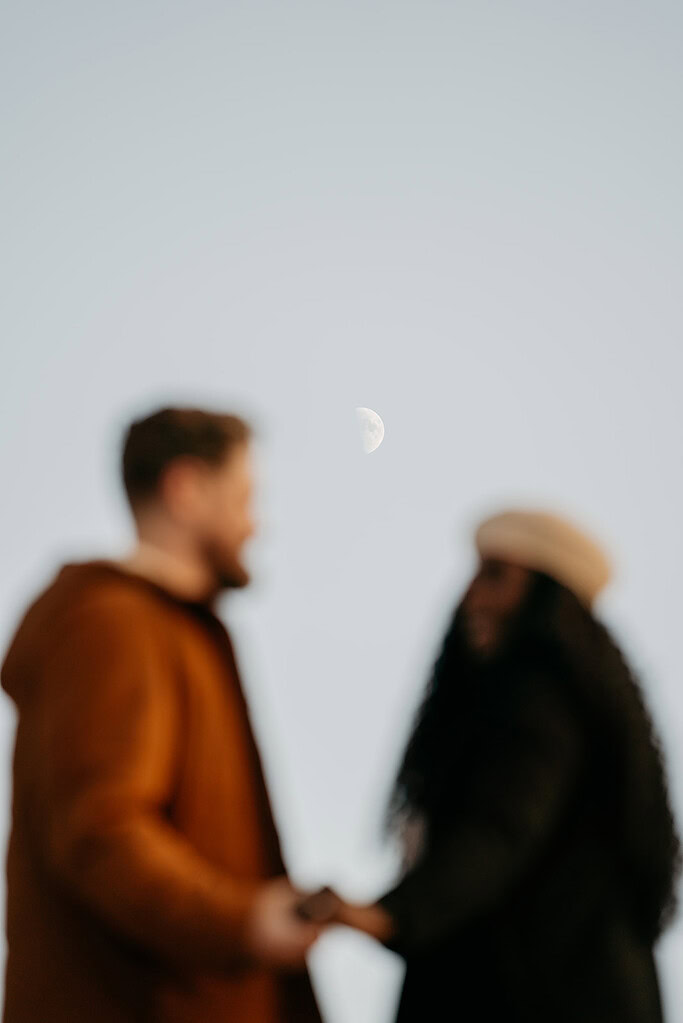 Silhouettes under moonlit sky in the evening.