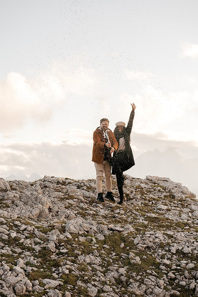 Couple celebrating with a champagne bottle outdoors.