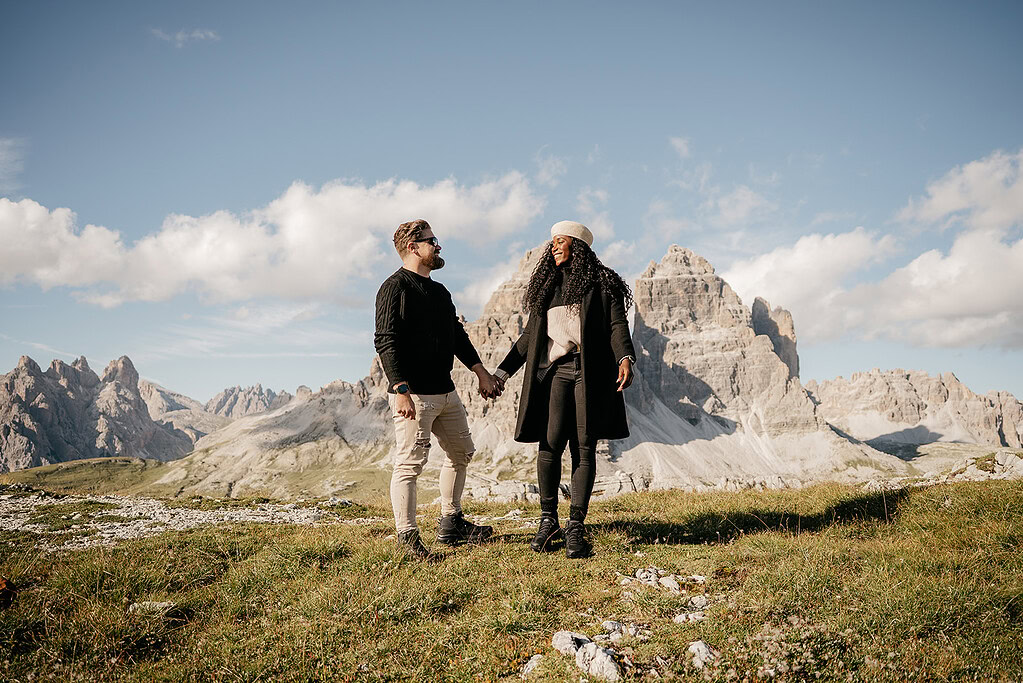 Couple holding hands in mountain landscape.