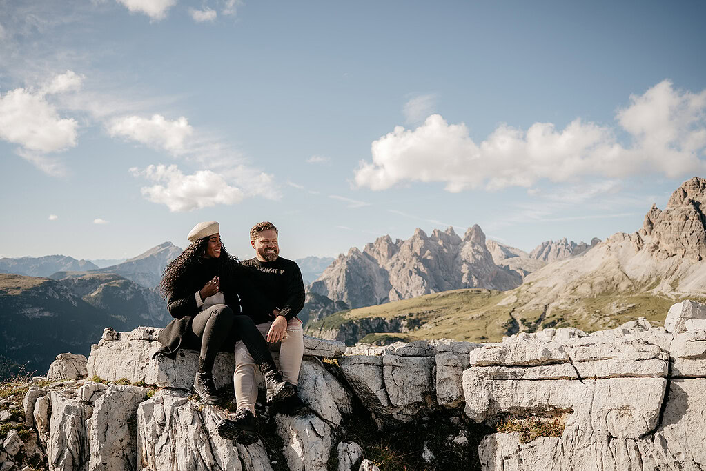Couple sitting on mountain enjoying scenic view.