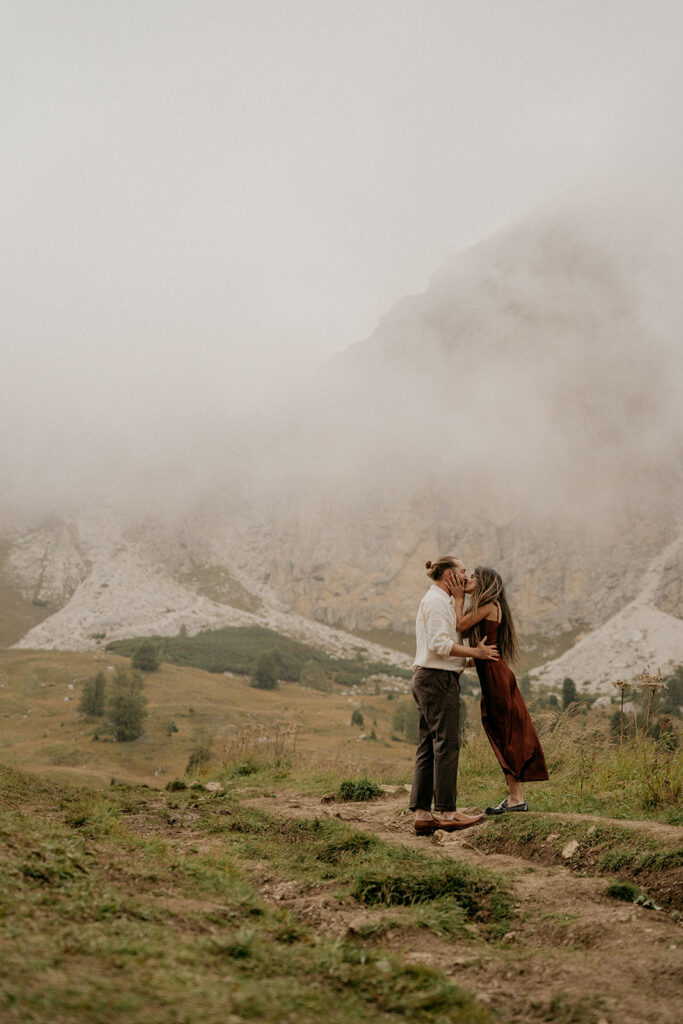 Couple kissing in a misty mountain landscape.