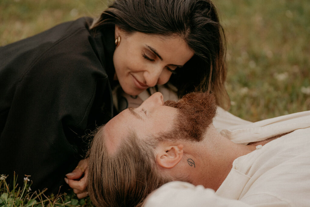 Couple lying on grass, gazing at each other.