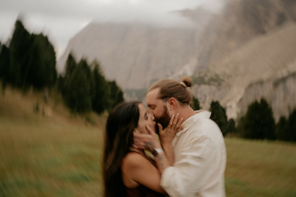 Couple kissing in a scenic mountain landscape.
