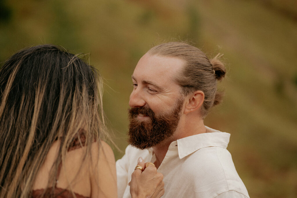 Couple smiling outdoors in nature setting.