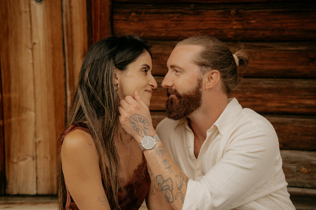 Couple gazing lovingly in rustic setting.