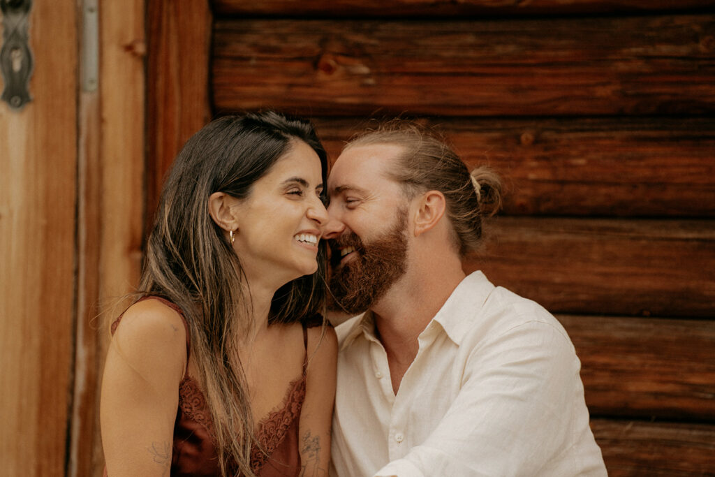 Happy couple smiling near wooden cabin