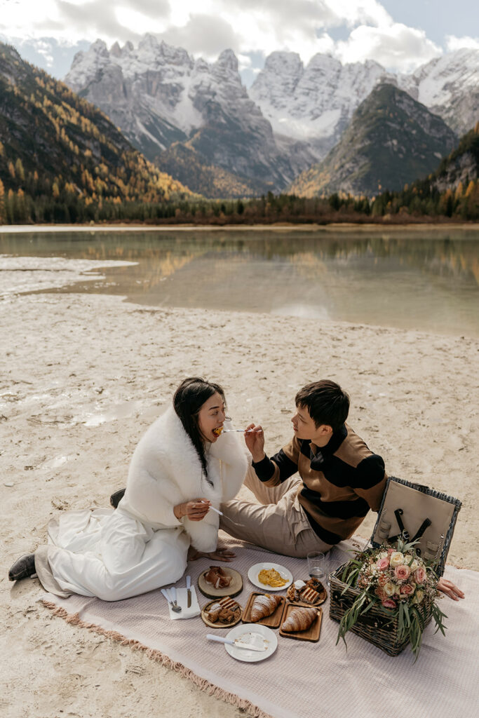 Couple enjoying picnic by scenic mountain lake.