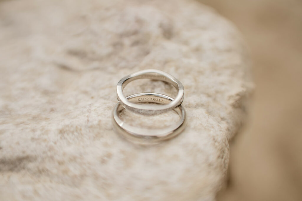 Two silver rings on a stone surface.