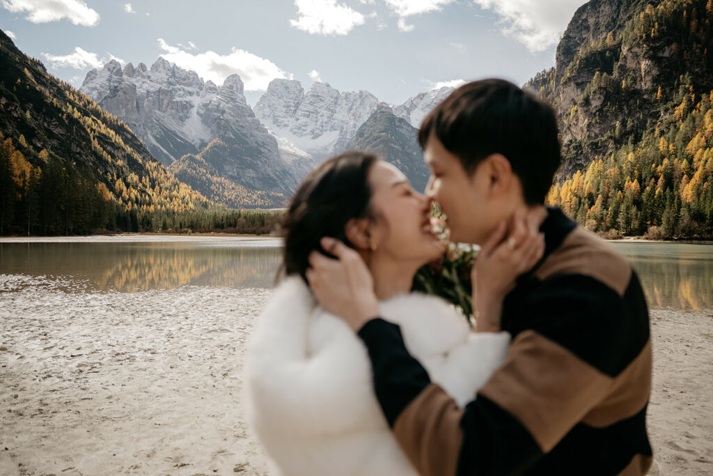 Couple kissing by a scenic mountain lake.