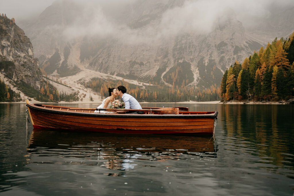 Couple kissing in boat on peaceful mountain lake.