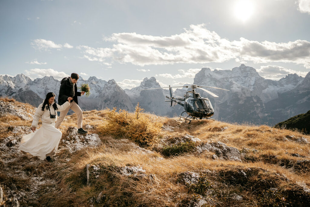 Couple hiking near helicopter in mountain landscape.