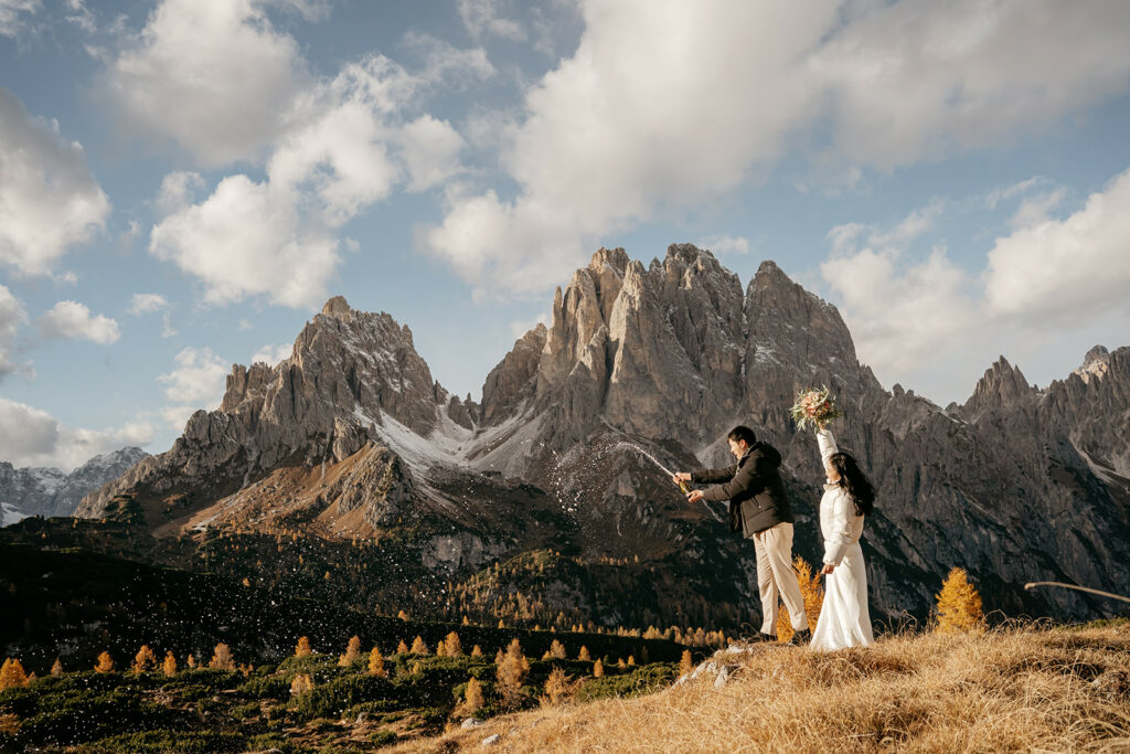 Couple celebrating with champagne in mountain landscape.