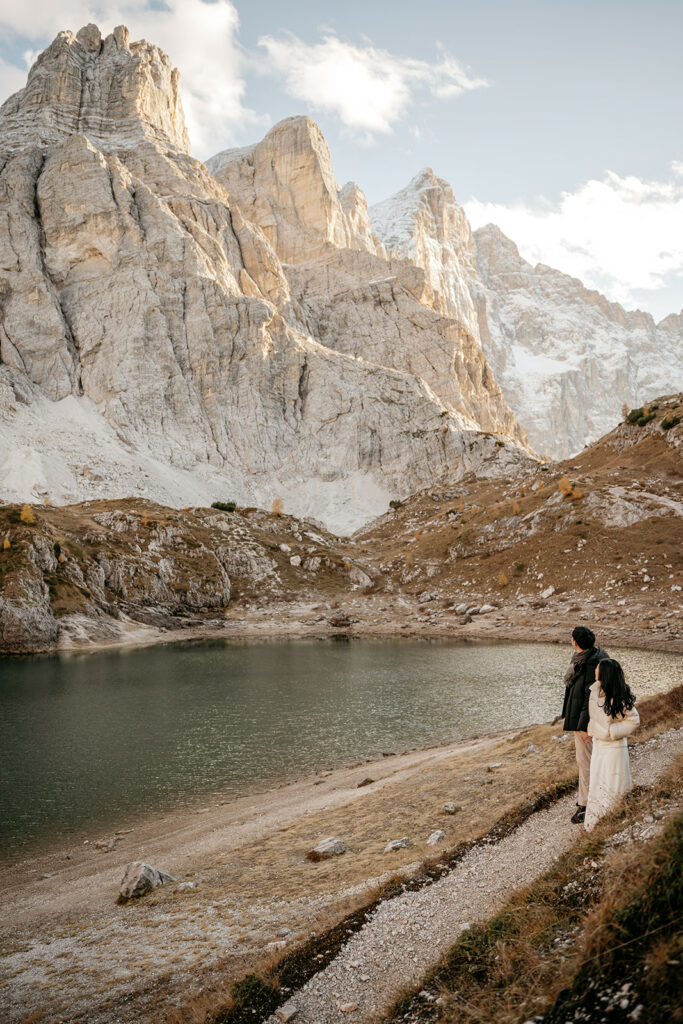 Couple admiring mountain lake and rocky peaks.