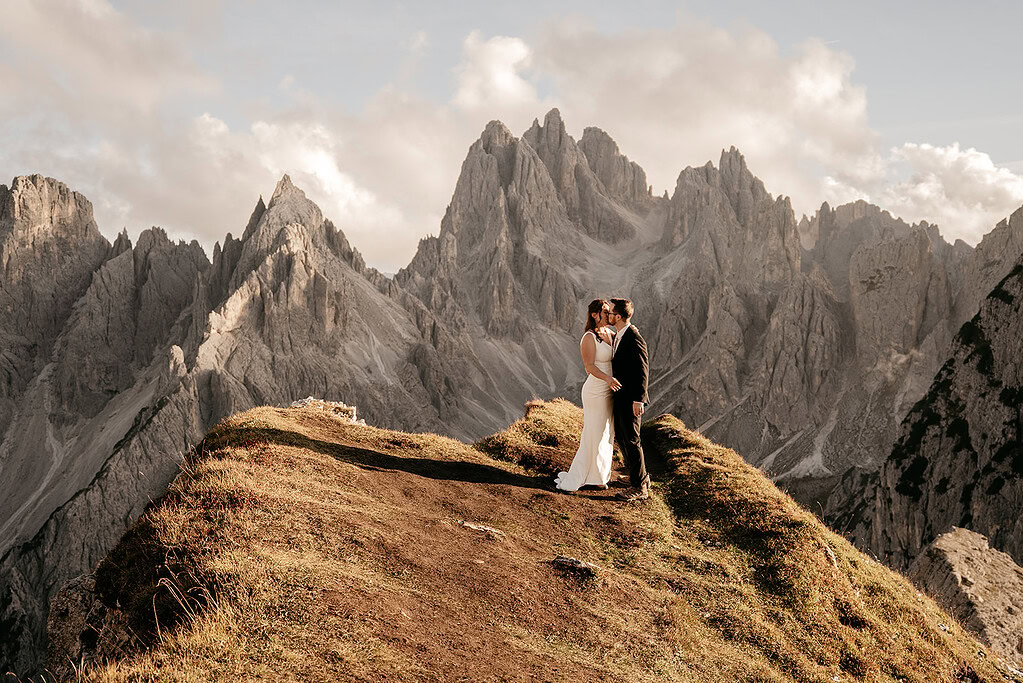 Couple kissing on mountain cliff at sunrise