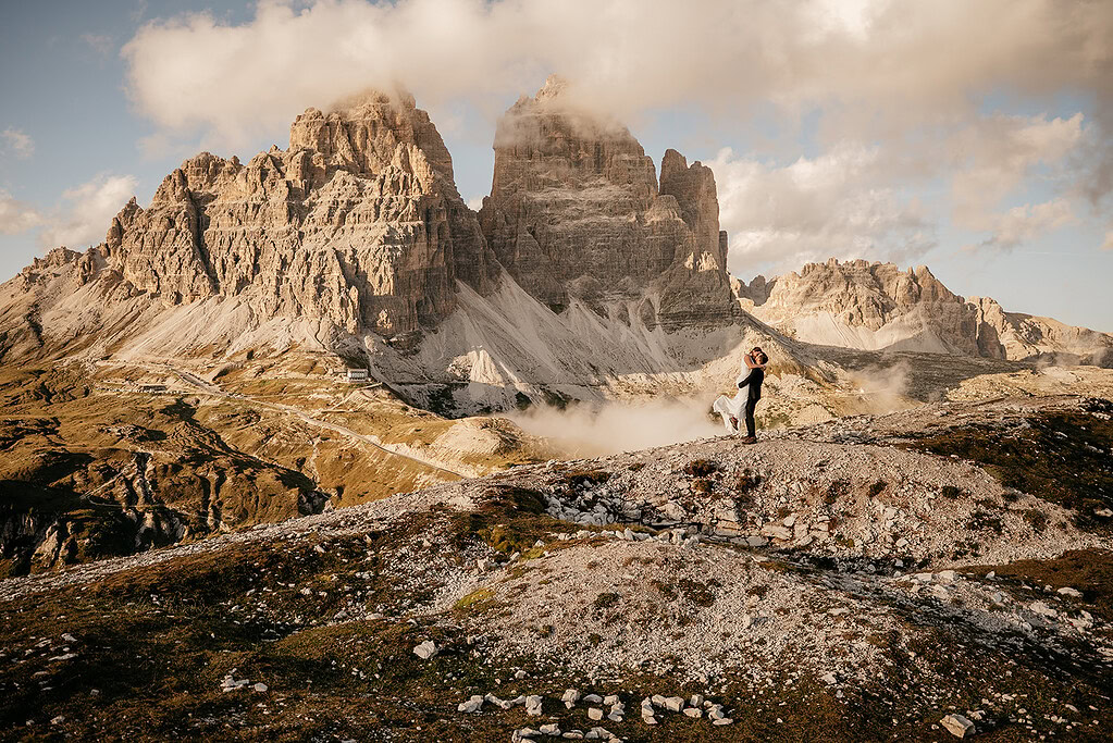 Couple embracing in front of stunning mountain landscape.