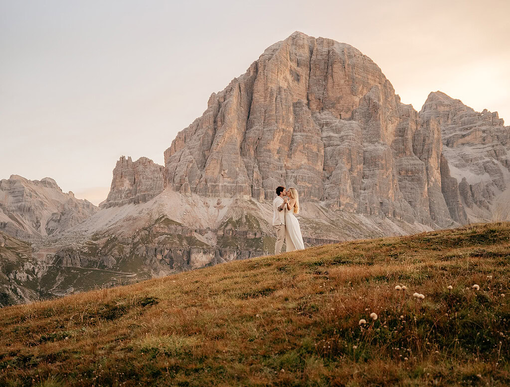 Couple embraces with mountain backdrop at sunset.