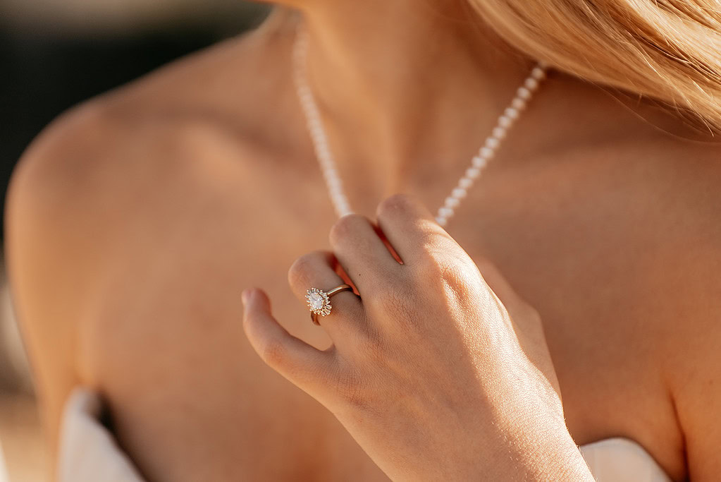 Woman wearing necklace and pearl ring.