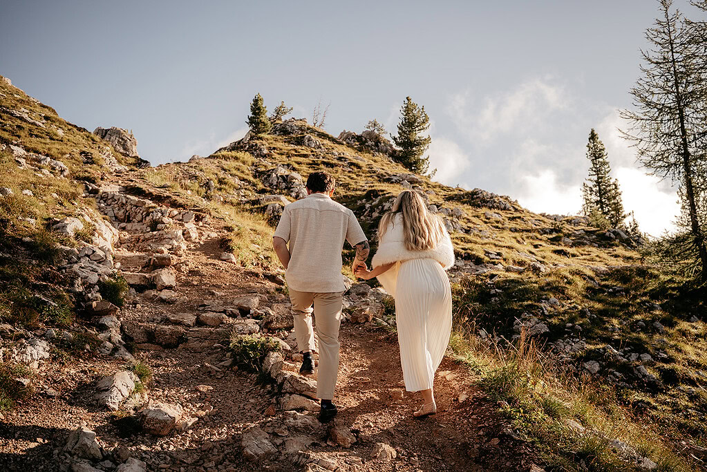 Couple hiking uphill on rocky mountain path