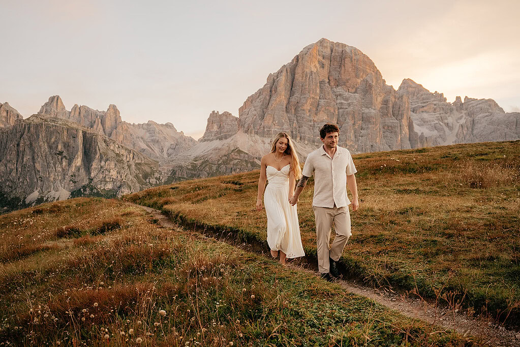 Couple walking in mountain landscape at sunset.