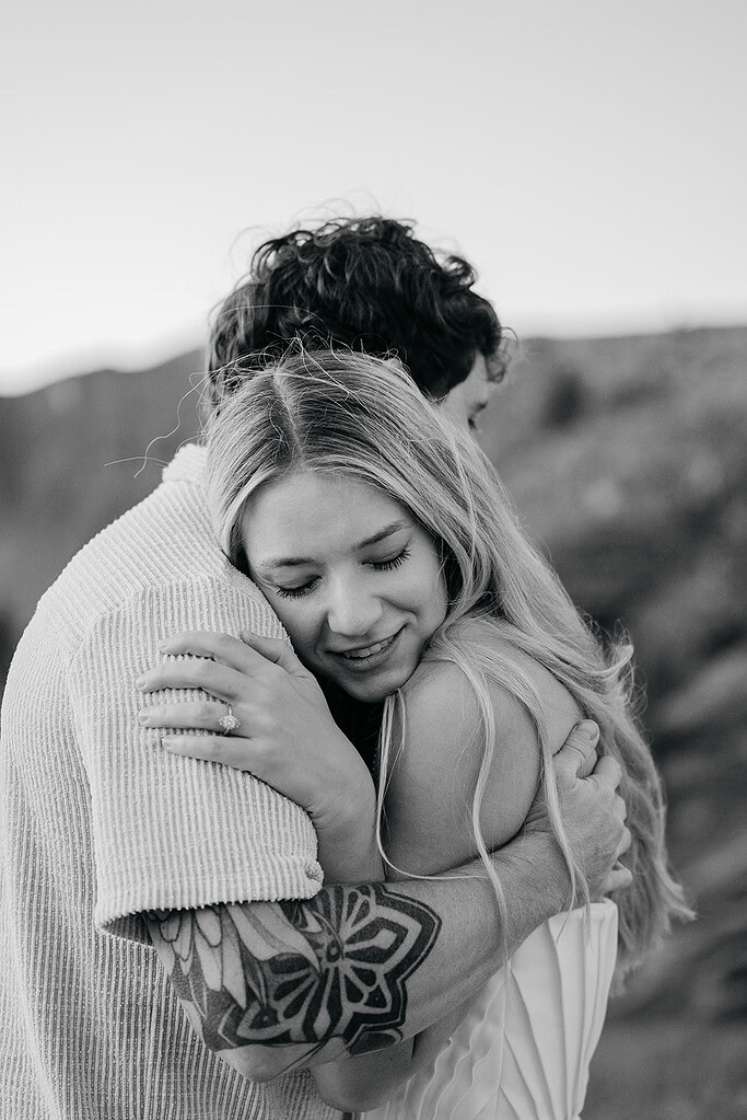 Couple embracing outdoors, with tattoos visible.
