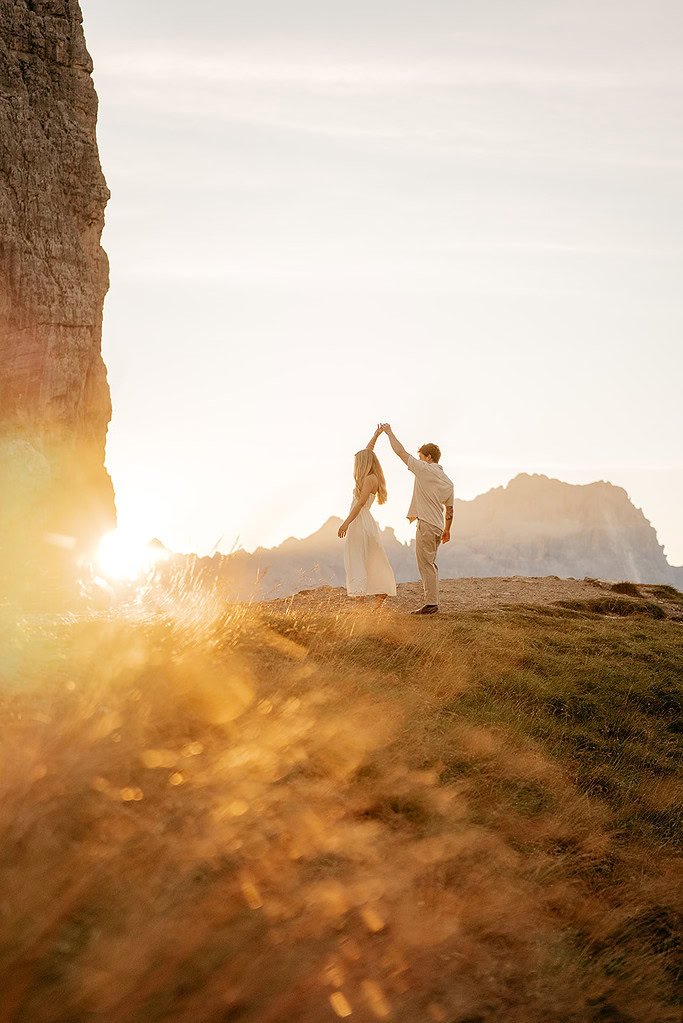 Couple dancing on hill at sunset, mountain view