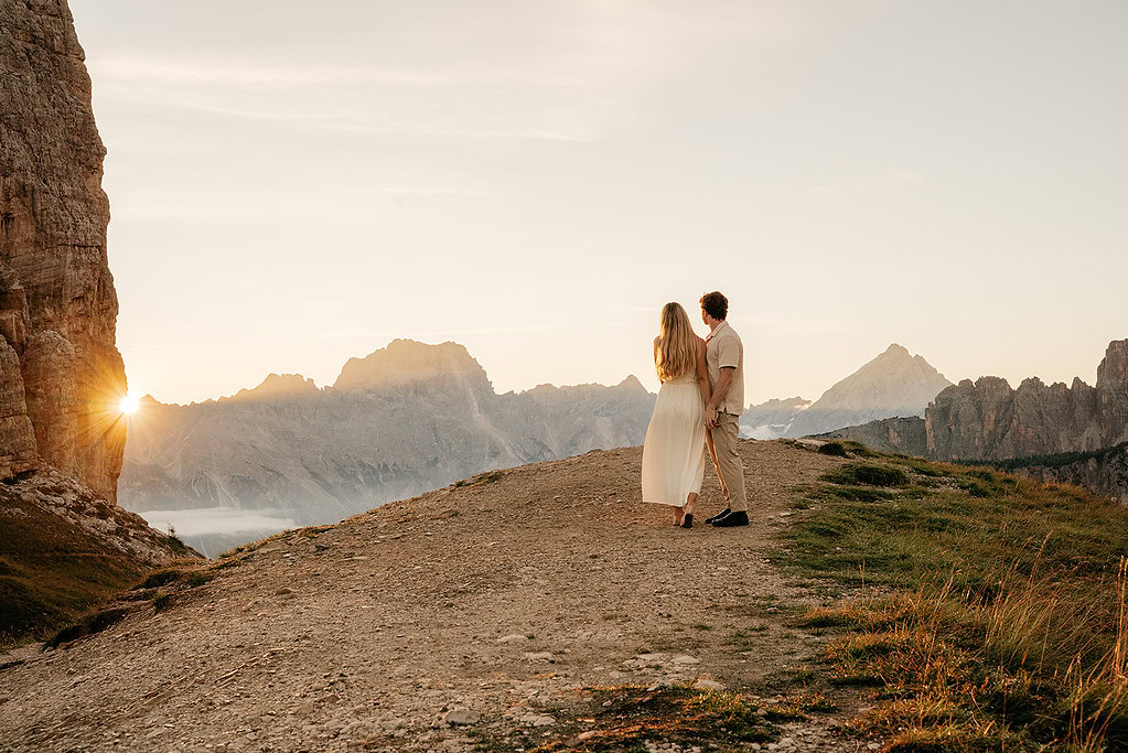 Couple walking mountain path during sunset.