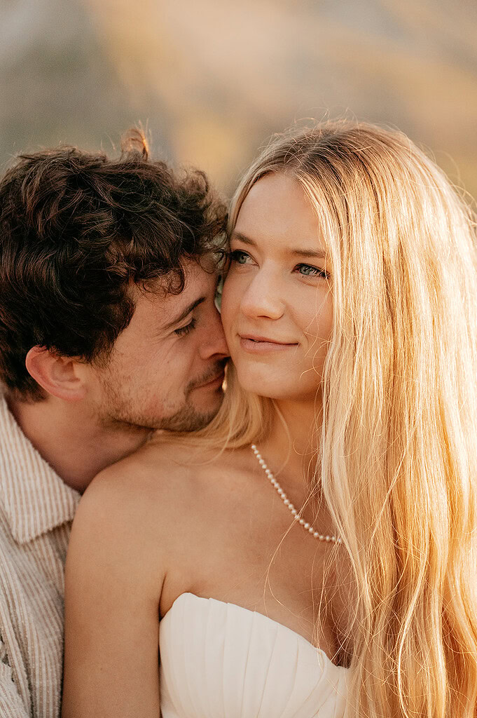 Couple embracing outdoors in soft sunlight.
