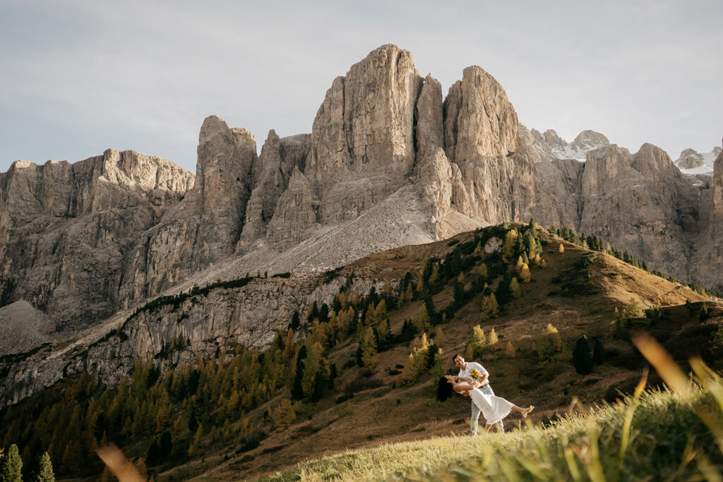 Couple dancing in mountain landscape at sunset.