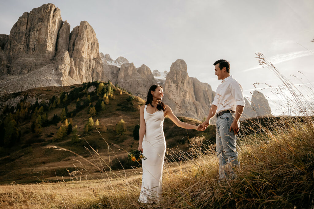 Couple holding hands in scenic mountainous landscape.