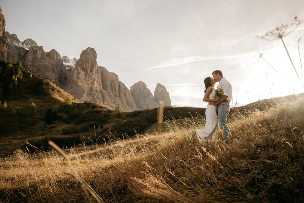 Couple kissing in mountainous landscape at sunset.