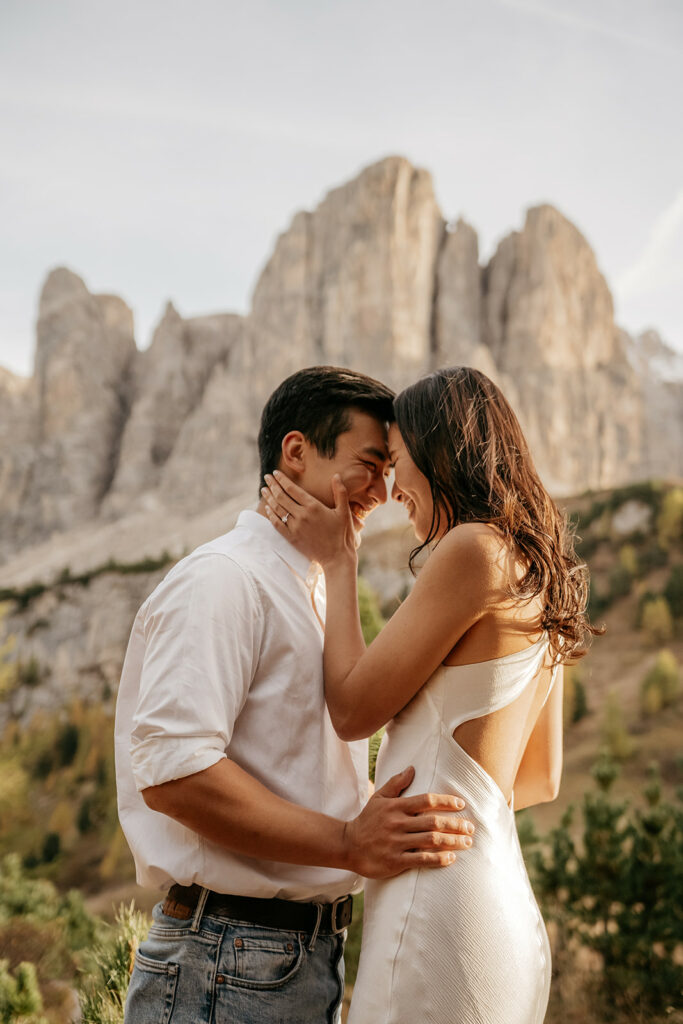 Couple embracing in mountain landscape, smiling affectionately.