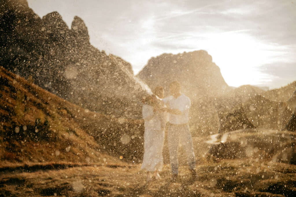 Couple celebrating in a sunlit mountainous area.