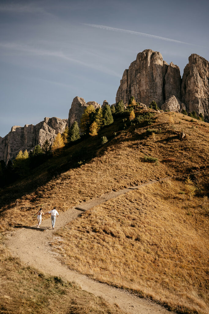 Couple hiking on mountain path, rocky peaks background
