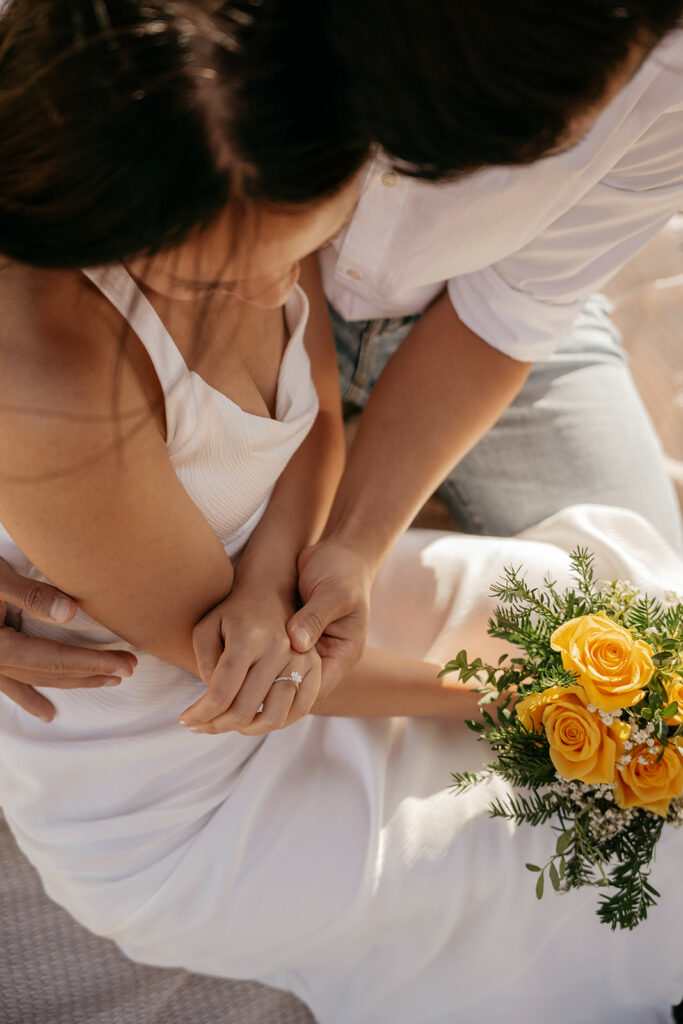 Couple holding hands with yellow roses bouquet.