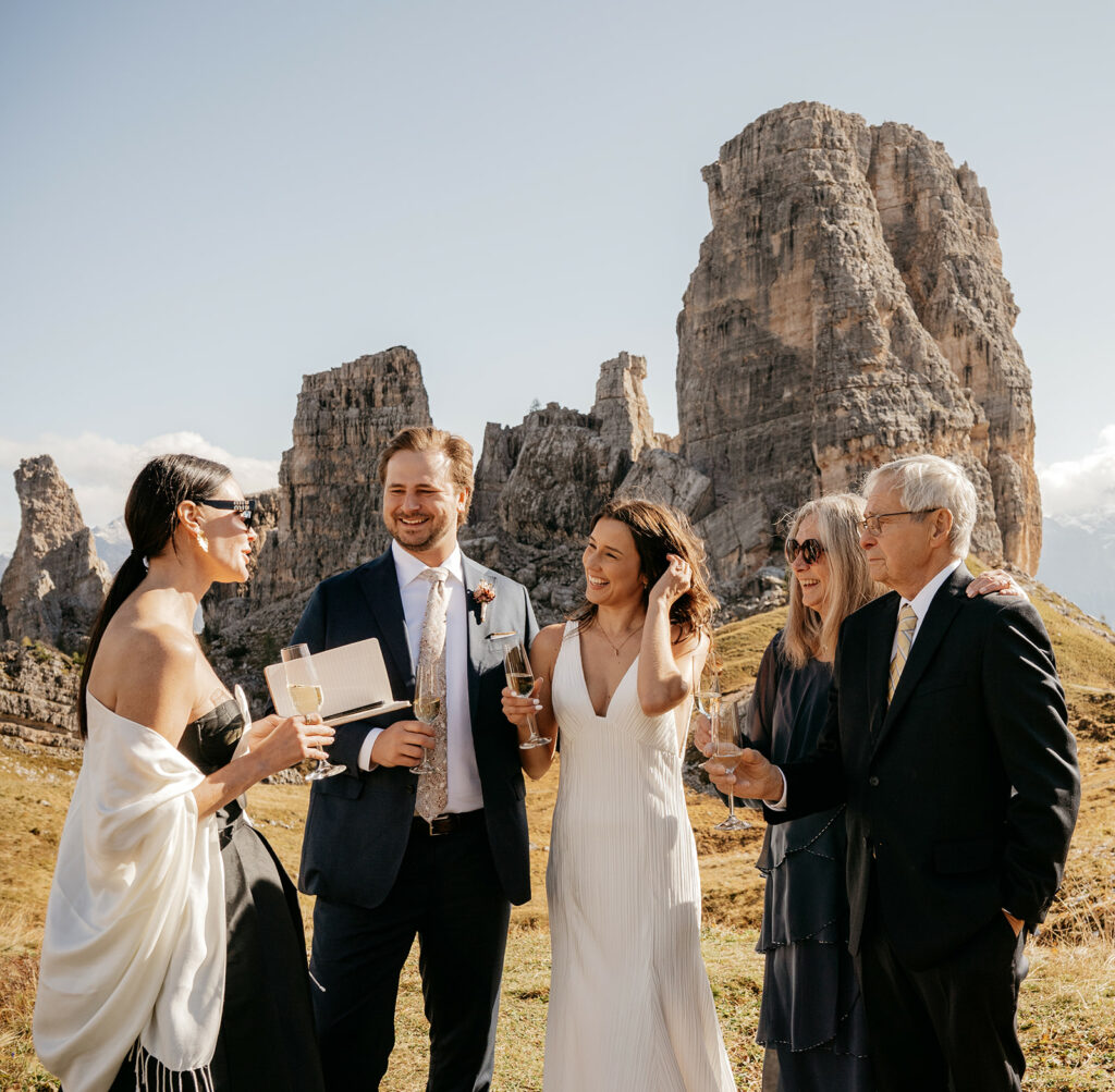 Group celebrating in mountains with champagne glasses.