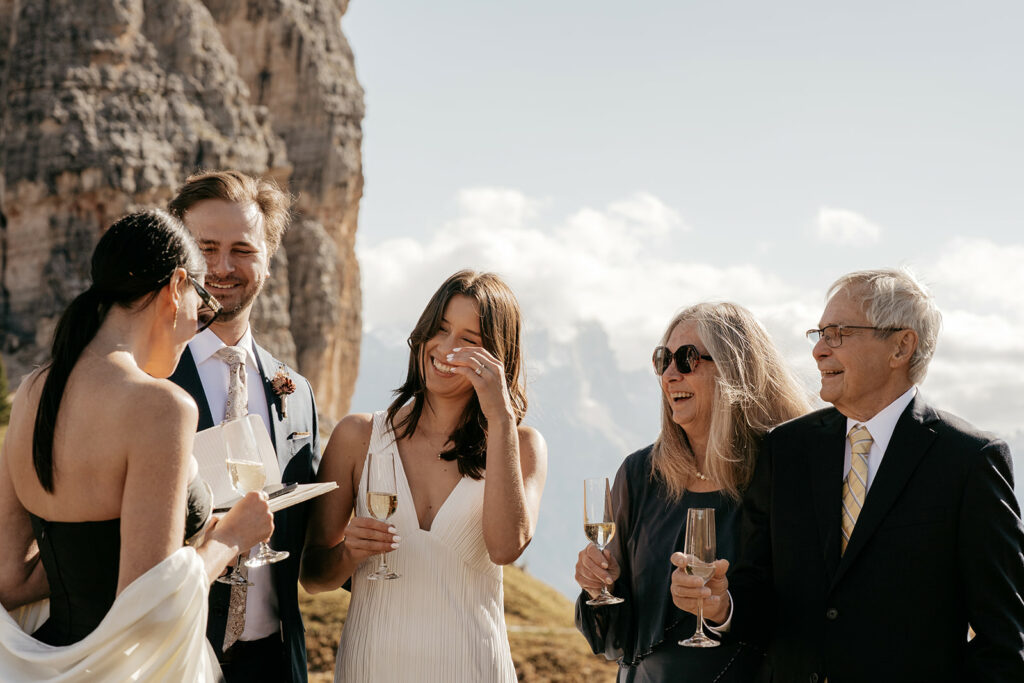 Group smiling with champagne outdoors at mountain wedding.