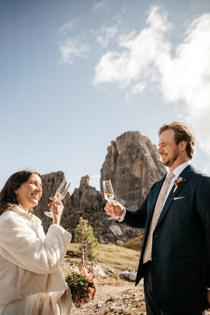 Couple toasting with champagne in mountain landscape.
