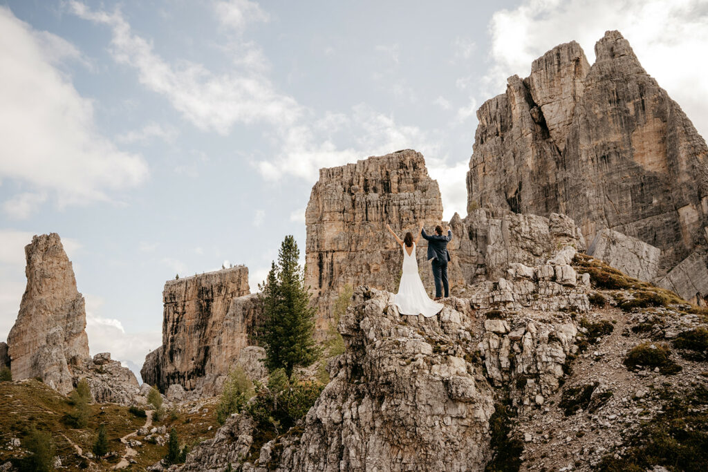 Couple celebrates on rocky mountain top.
