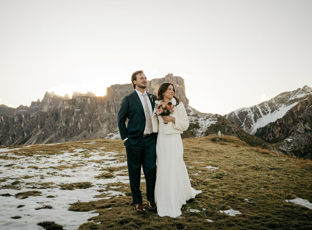 Couple posing in snowy mountain landscape during sunset.