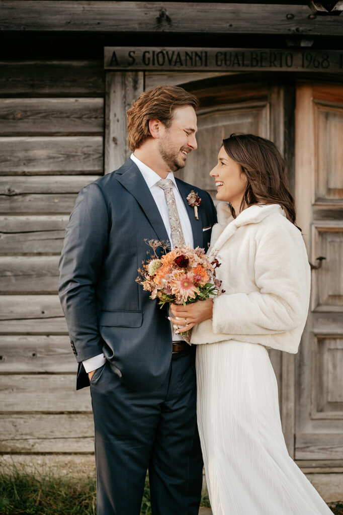 Smiling couple holding flowers in wedding attire