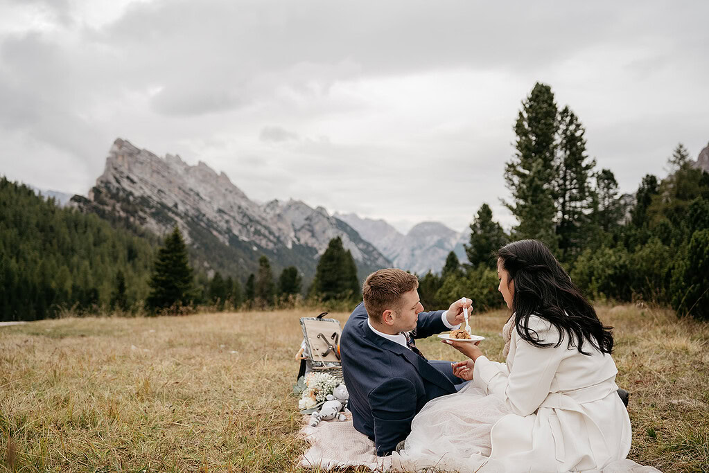 Couple picnicking in scenic mountain landscape.